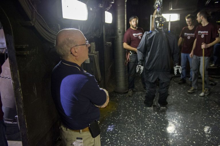 A humanoid robot undergoing balance and movement testing inside a bright research laboratory.